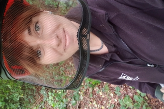 Woman looking at the camera through a face guard during coppicing