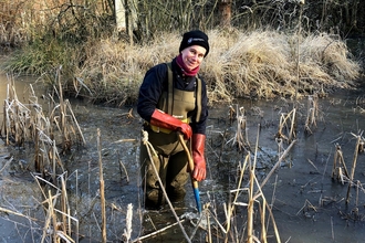 Woman in chest waders in a pond in cold weather by Catharine Jarvis