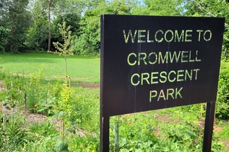 A sign saying 'Welcome to Cromwell Crescent Park; with the park in the background