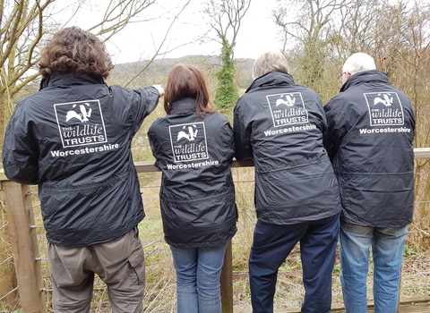4 people with their back to the camera to show off their Worcestershire Wildlife Trust logo'd jackets