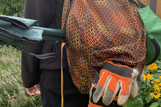 A bulging rucksack with a chair, gloves and first aid kit peeking out of it