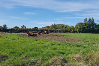 Machinery creating a shallow wetland scrape in a field by Emily Williams
