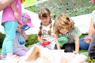 Several children holding magnifying glasses to look more closely at wildlife by Lauren Roberts