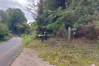 Matt stood with a brush-cutter with a road to the left