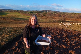 Trainee Jess scattering heather seed at Dropping Well Farm