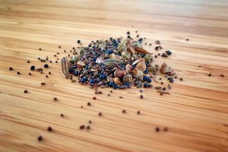 A small pile of various wildflower seeds on a wooden table