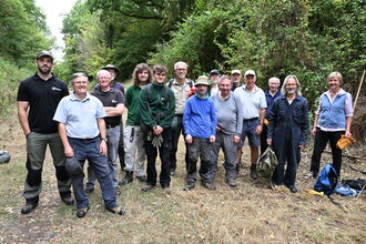 A group of volunteers on a wide path with trees on either side - all are posing and smiling for the camera