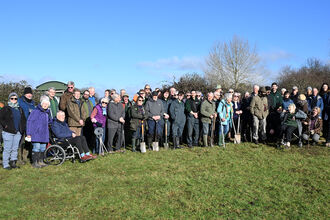 A large group of people in a field on a sunny day - they're (mostly) looking at the camera and smiling. Harry Green is to the right of the photo.