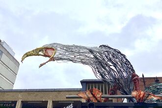 A photo of a giant sculpture of a seagull on top of a plinth made from old wire