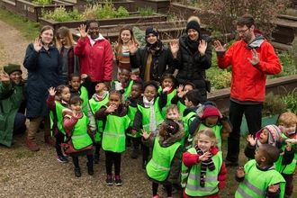 Nursery children and teachers/adults in a wildlife garden waving at the camera by Penny Dixie