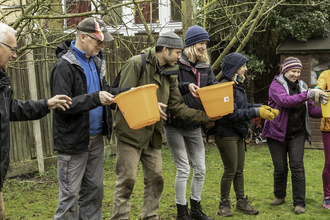 A group of people passing buckets along a line (by Penny Dixie)