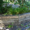 Photo showing a raised bed with plants in and the words 'created by the community for the community' around the bed (by Liz Yorke)