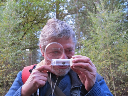 John Day looking through a magnifying glass 