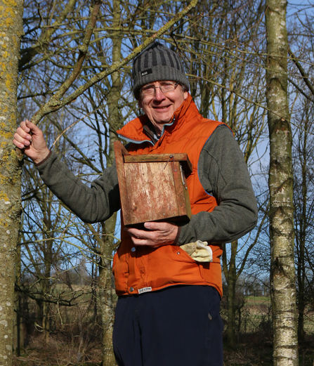 John Lashley holding a bird box as he's about to put it up in a tree by Wendy Carter