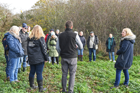 Group of people talking amongst trees and hedges by Brian Taylor