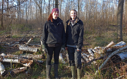 Two women standing in woodland and smiling for the camera by Iain Turbin