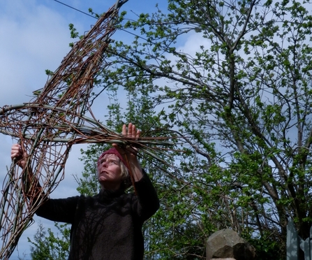 Artist Juliet Mootz holding one of her willow swift sculptures in the air