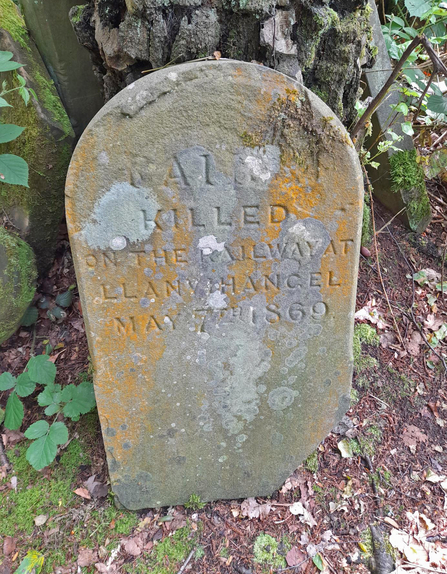 Gravestone for a dog in a woodland - the words say "RAI** killed on the railway at Llanvihangel May 17th 1869"
