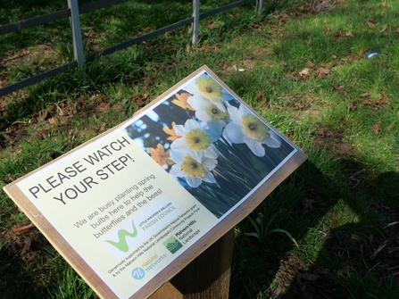 Sign asking people to watch their step because bulbs have been planted