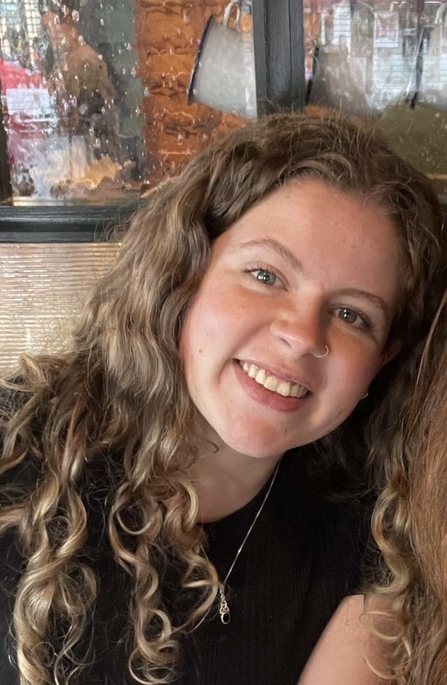 Woman with long curly hair smiling at the camera