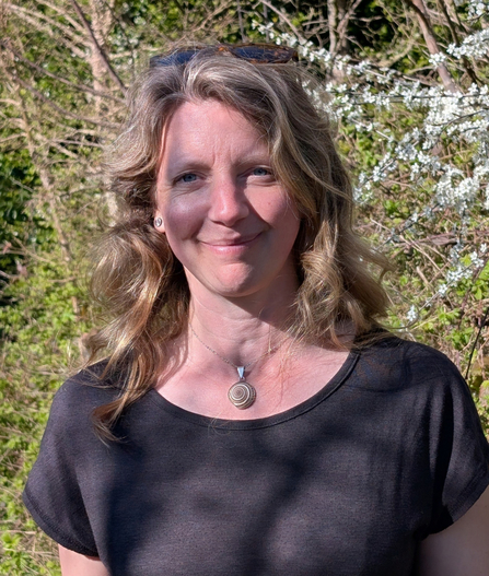 A woman with wavy blonde hair and sunglasses on top of their head smiling at the camera