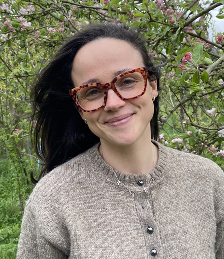 A woman with long dark hair and tortoiseshell-effect glasses smiling at the camera