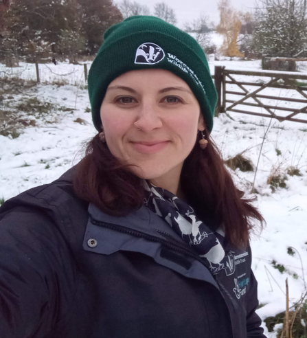 Woman in a green hat with snow behind her - she's smiling at the camera