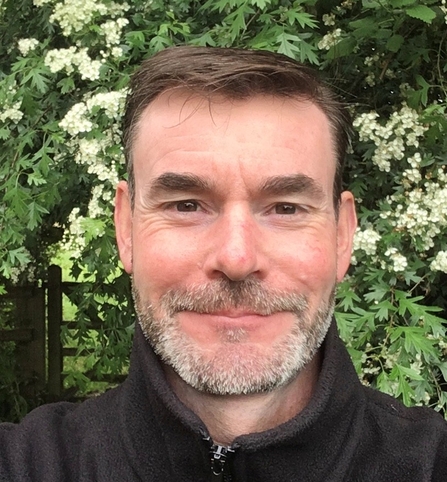 A man with short hair and short beard smiling at the camera