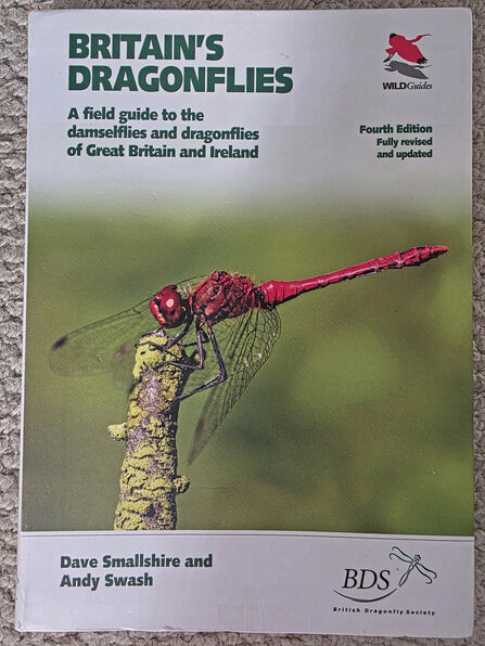 the front cover of 'Britain's Dragonflies' book - a field guide to the damselflies and dragonflies of Great Britain and Ireland by Dave Smallshire and Andy Swash. It features a photo of a red dragonfly with its wings folded forwards