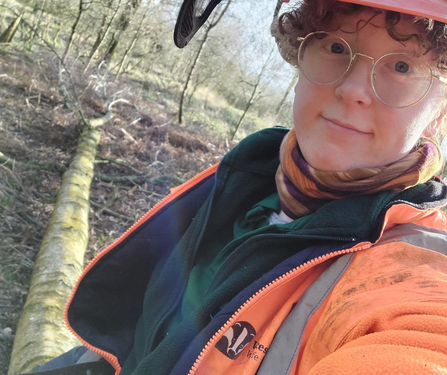 A photo of a person wearing protective gear and a helmet with curly hair and glasses