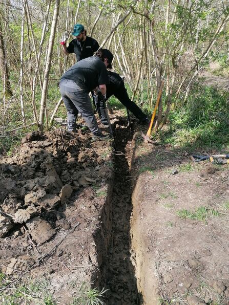 A group of trainees digging a trench in the ground 