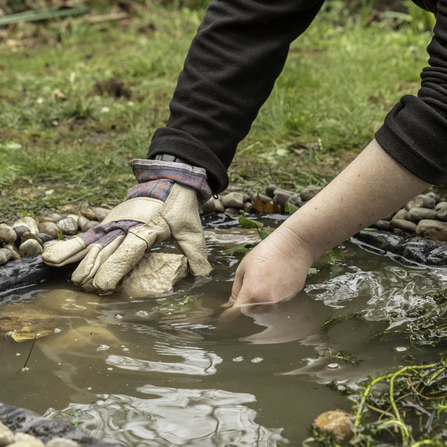 A pair of hands putting stones into a newly created pond