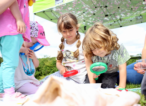 Several children holding magnifying glasses to look more closely at wildlife by Lauren Roberts