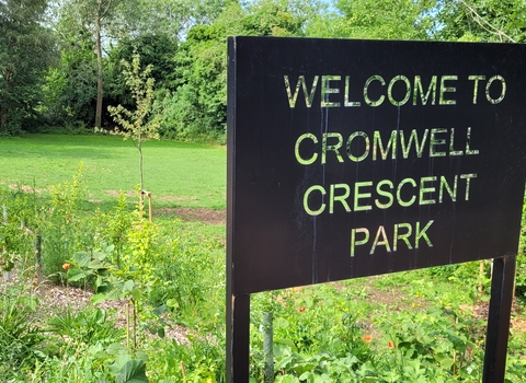 A sign saying 'Welcome to Cromwell Crescent Park; with the park in the background