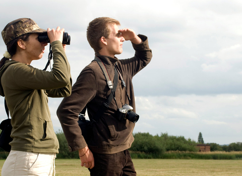 Two people looking through binoculars by Zsuzsanna Bird